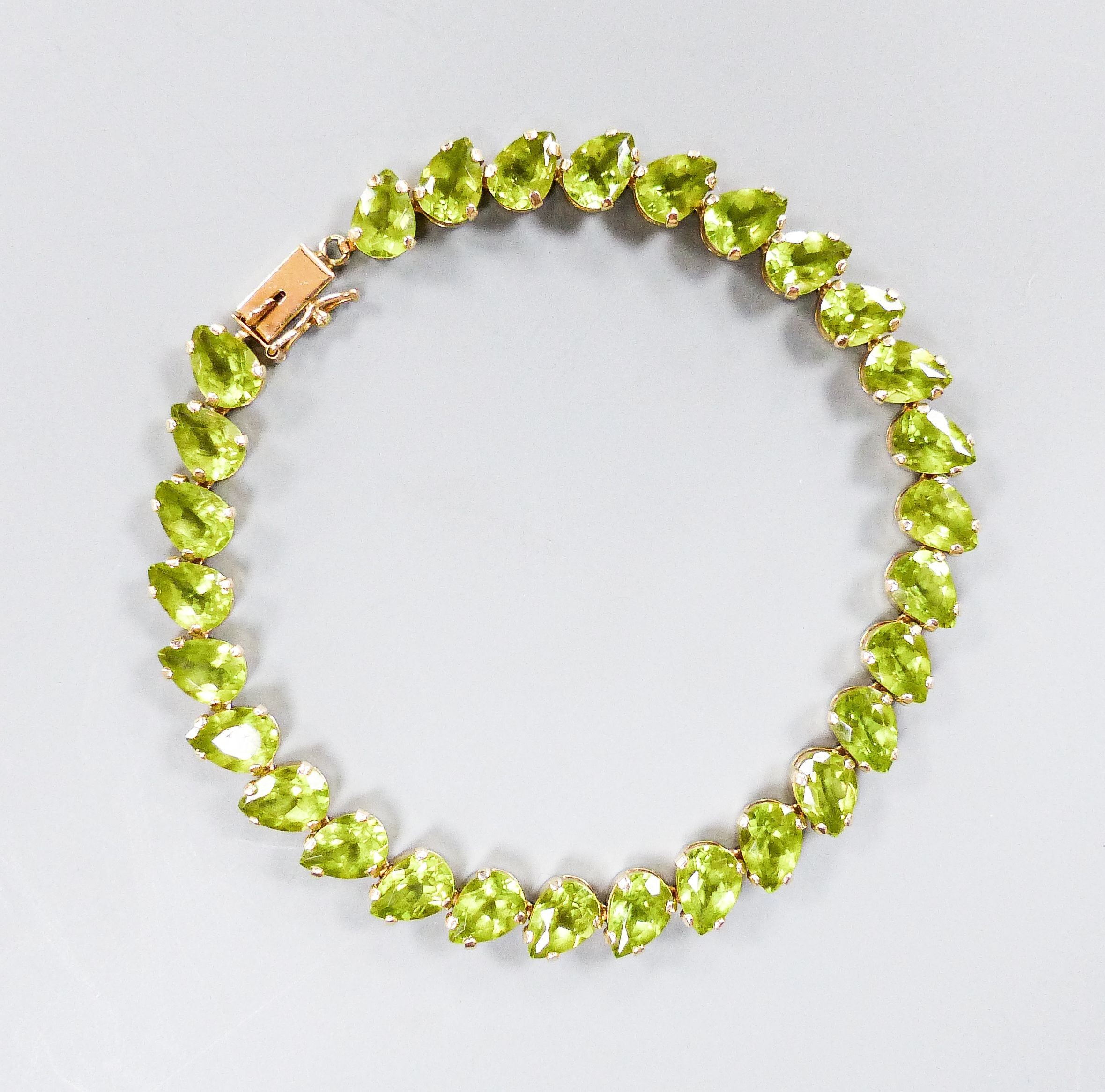 A modern 10k and pear cut peridot set line bracelet, 19cm, gross weight 9.4 grams.